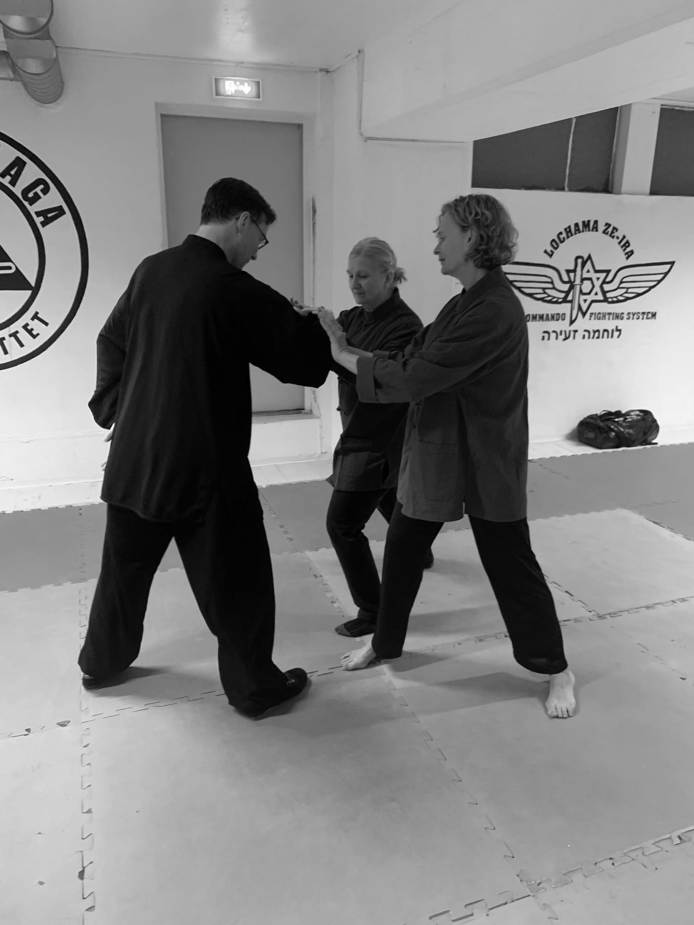 Tre utøvere trener Taiji med partner i klubbens sal på Kjeller